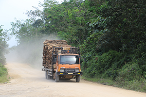 Logging truck driving down a dusty road