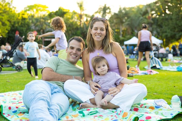 Family sitting on picnic rug on Perth Zoo main lawn